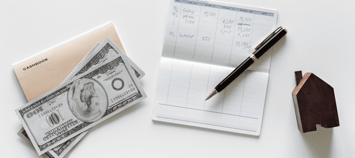 Checkbook and cash in $100 bills sitting on a table