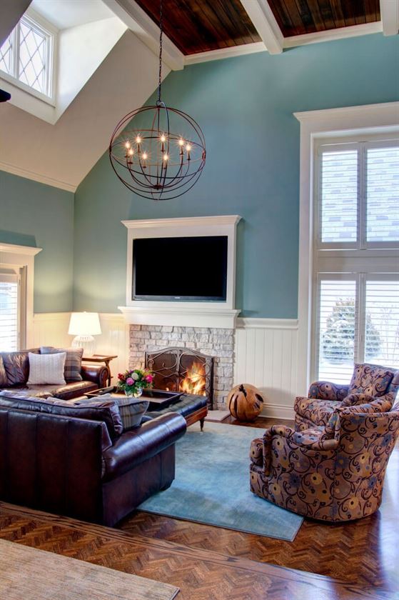 Living room with light blue walls and TV mounted over fireplace