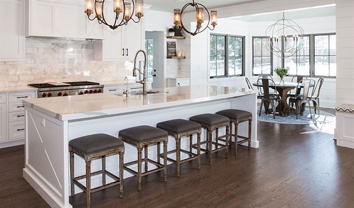Kitchen with dark wood floors, white cabinets, and an impressive, focal-point center island with stools