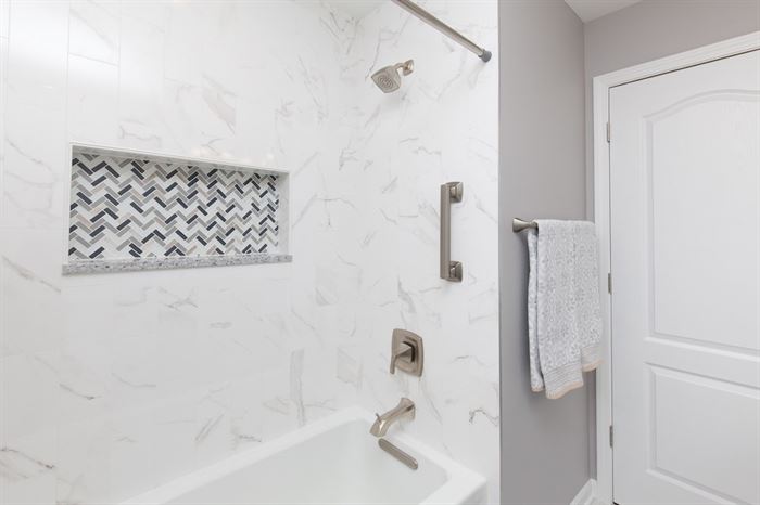 Renovated bathroom with shower/tub combo and a handrail for assistance