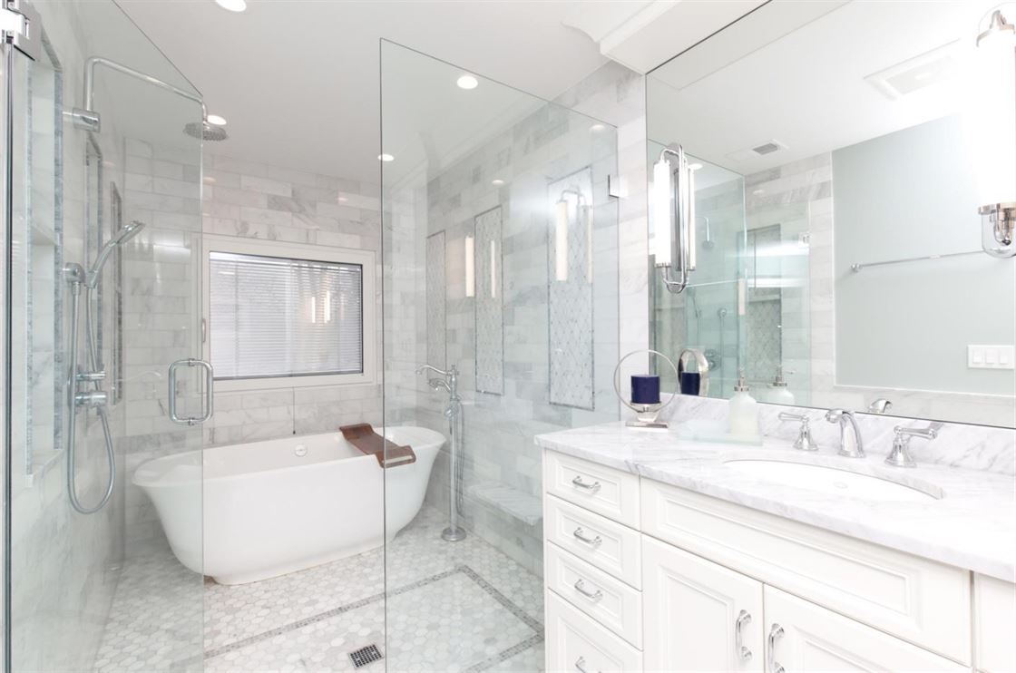 Marble bathroom with stand alone tub and white cabinets