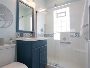 Blue and white bathroom with walk-in shower and claddagh symbol on the wall