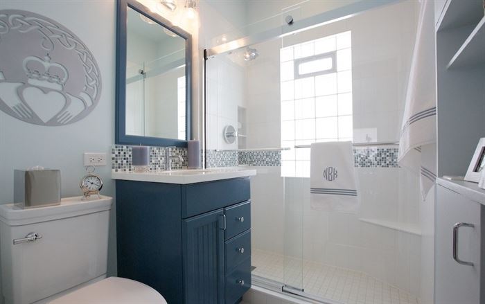 Blue and white bathroom with walk-in shower and claddagh symbol on the wall