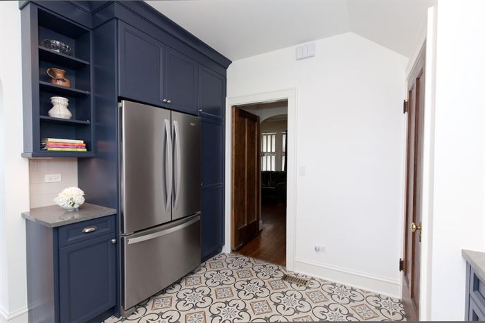 Completed kitchen remodel with blue lower cabinets cabinets around stainless streel fridge