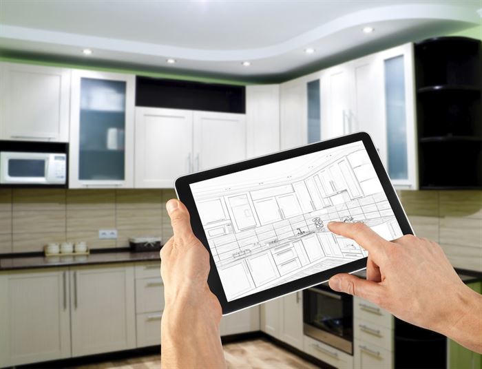 Person holding a tablet with a kitchen drawing in front of the renovated kitchen